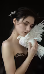 a woman in black holding a white bird in her hand