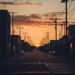 a empty street with lines across it and the sun setting in the distance