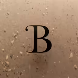 a close up of the letter b with tiny shells in the sand