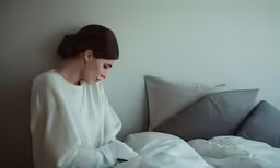 a woman with a bun in her hair sitting on a bed