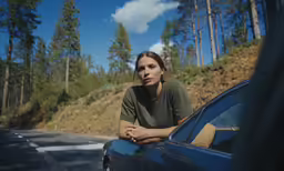 a woman sits on the hood of a car