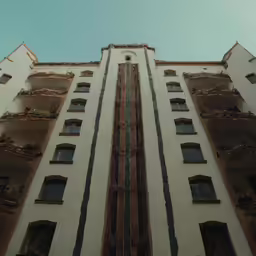 the bottom of a tall white building with many windows