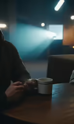 man sitting at table with coffee cup while listening to mp3 player