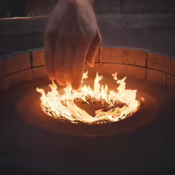 a hand is reaching into a round fire pit