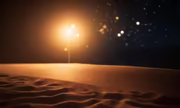 two light poles on top of a sandy surface