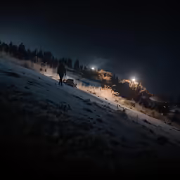 a man walking across a snow covered field at night