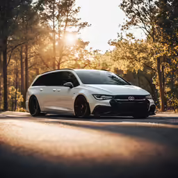 a white car is driving down a wooded road