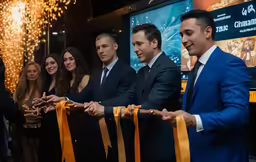 a group of people are standing in line to cut the ribbon