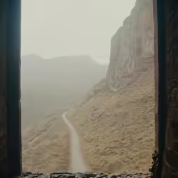 a view out an open window to the hills and road
