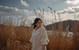 the young woman is standing by tall grass