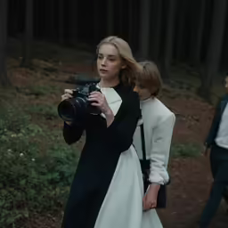 woman taking a photograph with a camera in the woods