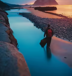 the man is walking out from the water carrying his bag
