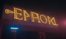 a neon sign reads expox at night time