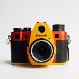 a yellow camera with a black lens in front of a white background