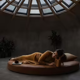 a woman in yellow laying on a large circular chaise