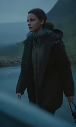 a girl walking towards a car in the rain