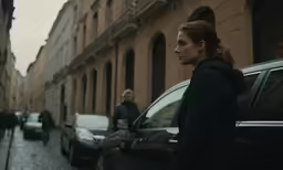 a young woman standing in the street with her back to the camera and people walking beside her