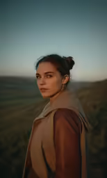 a woman with a bun hairdo in a brown leather jacket