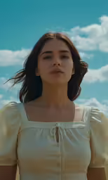 a woman wearing a white dress looks up into the sky