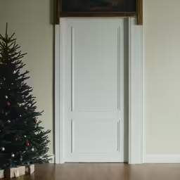 a christmas tree sits under the door on a wooden floor