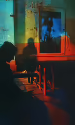 silhouette of a man sitting at table in front of television