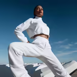 a woman in white clothes posing with her hands on her hips