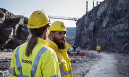 two construction workers wearing yellow jackets and hardhats