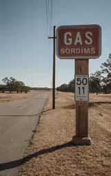 there is a sign for a gas station next to a road