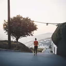 a woman running down the street in front of some houses
