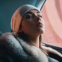 a woman in a winter coat looking out of the window