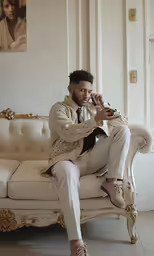 a man sitting on a couch drinking something