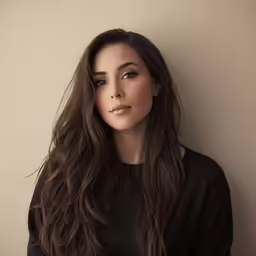 a beautiful young woman standing next to a wall