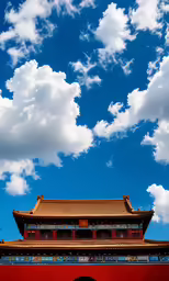 a red wall and two tower are under cloudy skies