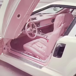the interior of an old white car with pink dash lights and leather seats