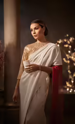 the beautiful woman in a white and gold gown is posing