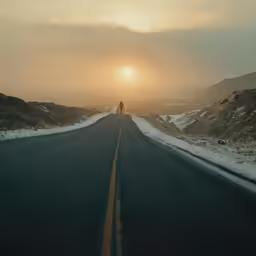 a man stands in the middle of a road with the sun behind him
