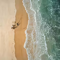 two people standing on the beach watching the water