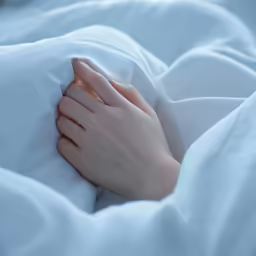 a close up image of a person with white sheets and their hands covering a pillow