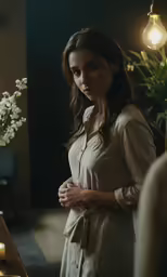 a woman standing in front of some flowers and lit candles