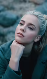 a woman in a coat sitting next to rocks