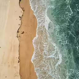 an aerial view of the ocean and sand and waves
