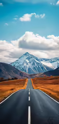 the asphalt road curves into the distance as mountains loom across it
