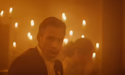 the man is looking at the camera in a darkened room