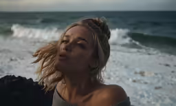 a woman standing on top of a beach next to the ocean