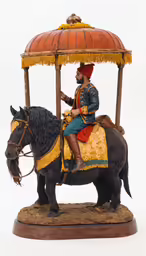 a figurine sits on a miniature horse