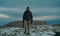 a man in winter gear on top of a snow covered hill