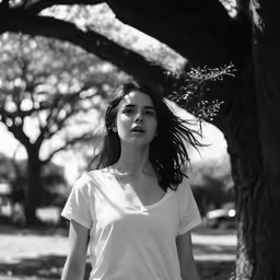 a woman in white shirt standing near a tree
