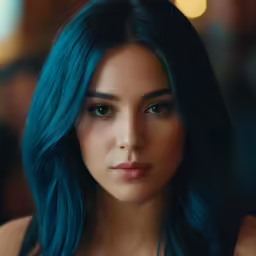 a girl with blue hair looks directly into the camera