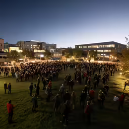 a large group of people standing in a field outside at night