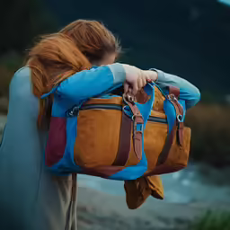 a woman is carrying a large brown and blue bag